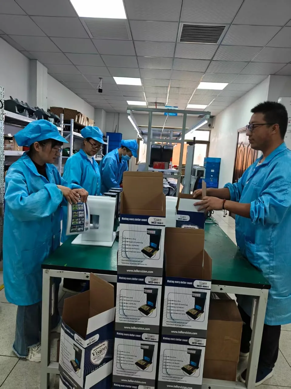 Staff packing finished Vision MCD-900-1 detectors into Tellervision boxes marked Making every dollar count